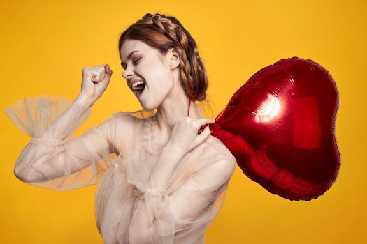 cheerful woman heart balloon holiday Valentine's Day yellow background. High quality photo