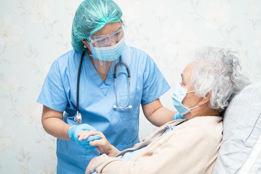 Asian doctor wearing face shield and PPE suit to check patient protect safety infection Covid-19 Coronavirus outbreak at quarantine nursing hospital ward.