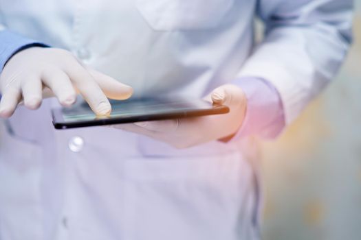 Asian senior or elderly old lady woman patient holding in her hands digital tablet and reading emails while sitting on bed in nursing hospital ward, healthy strong medical concept