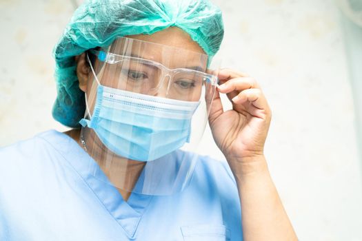 Asian doctor wearing face shield and PPE suit to check patient protect safety infection Covid-19 Coronavirus outbreak at quarantine nursing hospital ward.