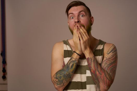 handsome man with tattoos on his arms fashionable hairstyle emotions. High quality photo