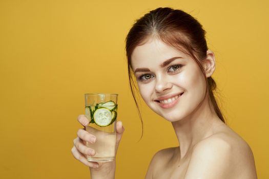 woman with cucumber drink vitamins body care yellow background. High quality photo