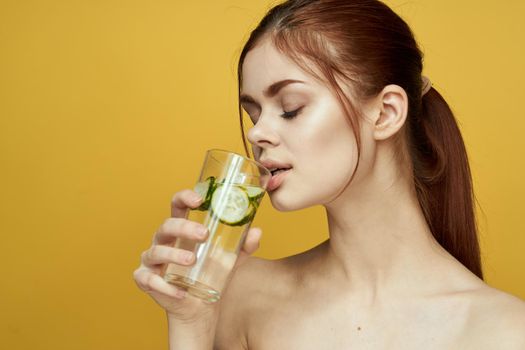woman with cucumber drink vitamins body care yellow background. High quality photo