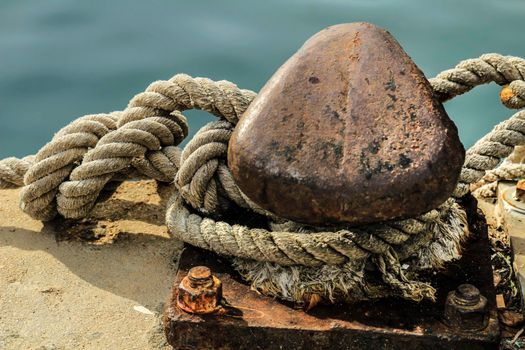 Rusty mooring bollard with tied rope in the port of Santa Pola, Alicante, Spain
