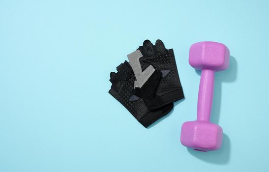 black ports gloves, pair of purple dumbbells on a blue background, healthy lifestyle. Top view
