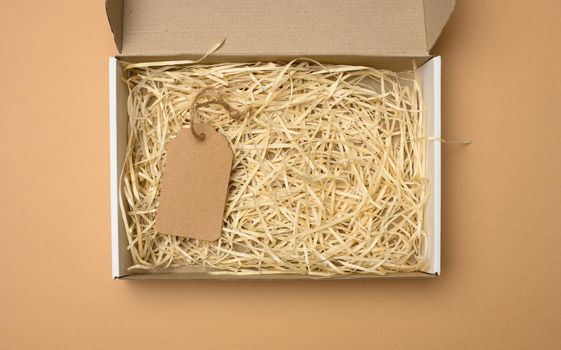 empty rectangular open corrugated paper box with sawdust inside. Packaging, containers for transportation on a brown background