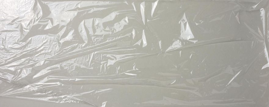 texture of crumpled transparent polyethylene on a gray background, full frame. Banner