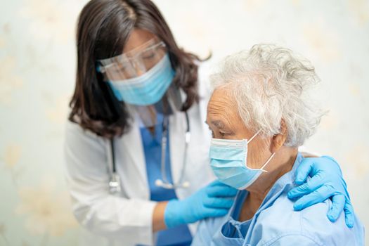 Asian doctor wearing face shield and PPE suit to check patient protect safety infection Covid-19 Coronavirus outbreak at quarantine nursing hospital ward.