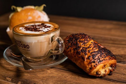 terni,italy october 26 2021:sweet croissants with cream and cappuccino on a wooden surface