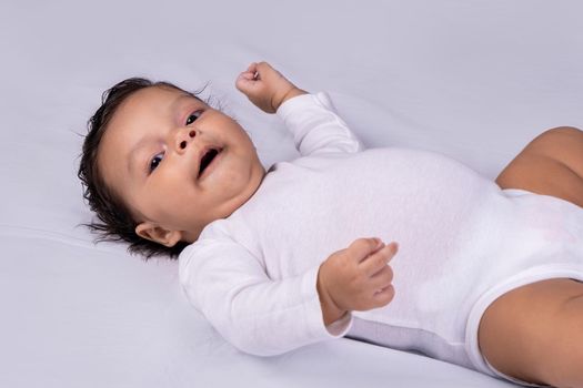 Infant lying on his back smiling and looking at the camera