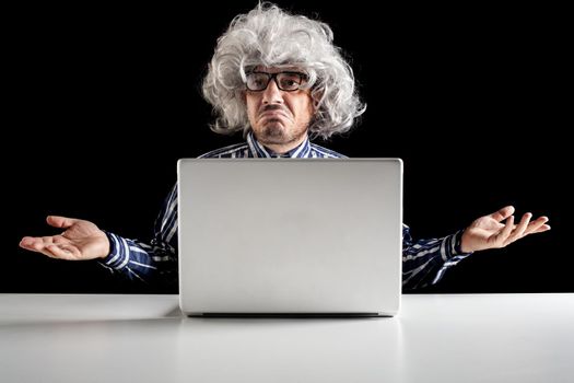 A bewildered senior, typical boomer, does not understand how to use the laptop computer on black background