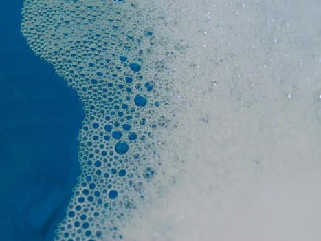 Close-up picture of their pattern in the bubbles of bath foam in blue water