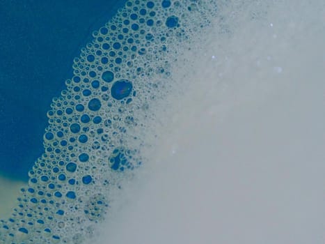 Close-up picture of their pattern in the bubbles of bath foam in blue water