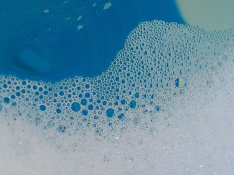 Close-up picture of their pattern in the bubbles of bath foam in blue water