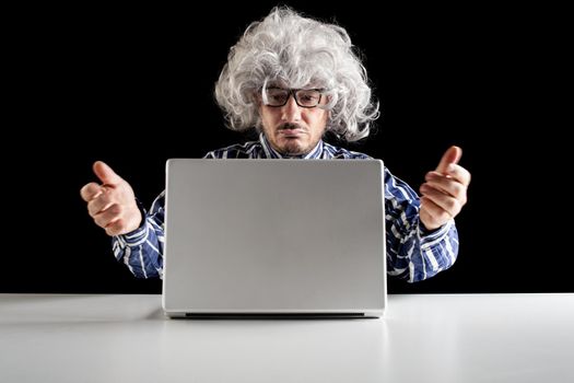 A bewildered senior, typical boomer, does not understand how to use the laptop computer on black background
