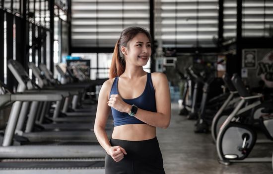 Portrait of confident beautiful asian fitness woman standing after exercise in gym. Concept of slim and healthy happy girl workout.