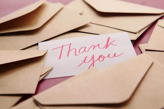 thank you message and envelope on wooden table.