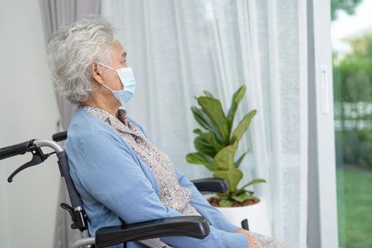 An elderly woman sitting on wheelchair looking out the window for waiting someone. Sadly, melancholy and depressed.