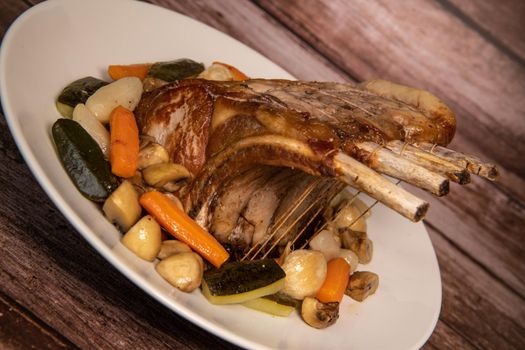 Pork ribs on turntable, Roasted pork ribs with bone, Entrecote, Roasted fresh meats. Organic food, Meat with spices: pepper, salt, bay leaf, rosemary and its vegetables, High quality photo