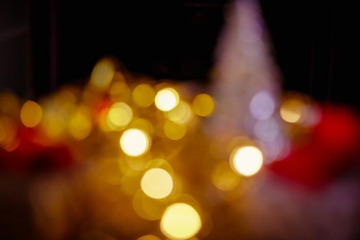 Christmas New Year boxes with a red bow. Yellow garland, light in dark room out of focus. Artistic bokeh.