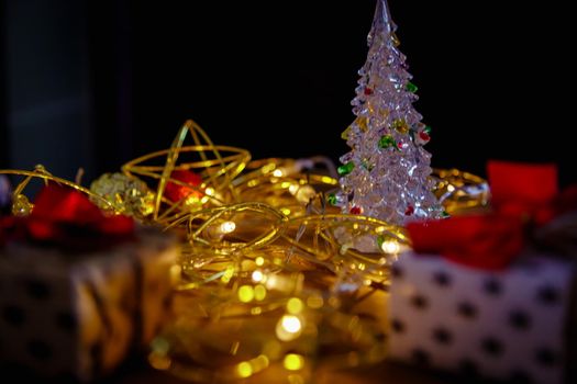 Christmas new year boxes with surprise and red bow. Yellow garland, lights in a dark room.