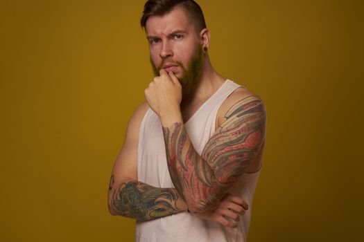 bearded man in white t-shirt with tattoos on his arms posing serious look. High quality photo