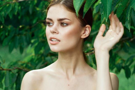portrait of a woman attractive look bare shoulders green leaves cropped view. High quality photo