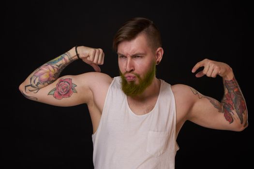 bearded man with tattoos on his arms gesturing with his hands dark background. High quality photo