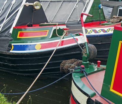 a close up of traditional british narrow boats painted in bright colors moored to a canal bank