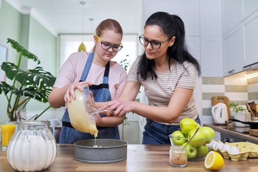 Mom and teenage daughter preparing apple pie together, at home in the kitchen. Family, parent teenager relationship, lifestyle, eating at home concept