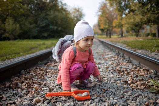 dangerous situation with children. cute toddler baby girl sits on the railroad tracks alone.