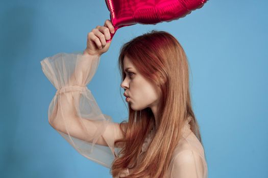 cheerful woman red heart in the hands of the balloon blue background. High quality photo