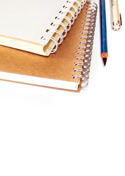 White and brown spiral notebook with pencil and pen