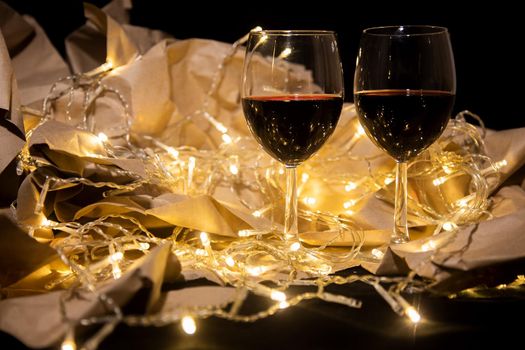 two glasses of red wine stand in a shining garland. romantic date concept. celebration concept
