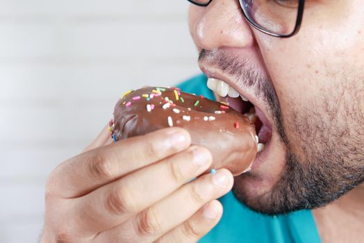 young man open his mouth eating donut , selective focus