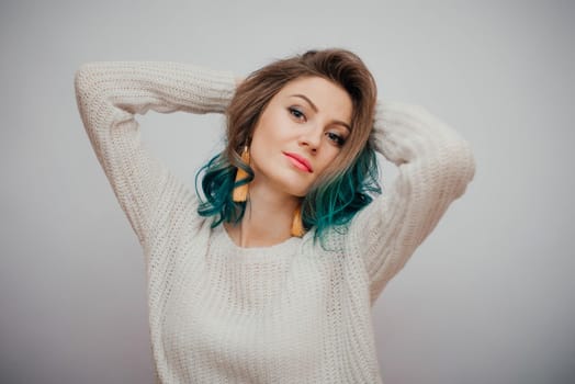 Pretty woman with colored hair on a white background. Long yellow earrings in contrast with turquoise hair.