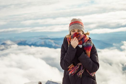 Portrait of adventure woman walking in winter in the mountains, clouds above the mountains background