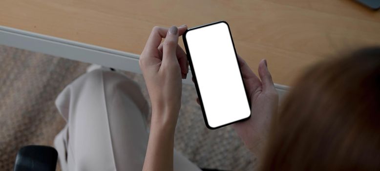 Mockup image blank white screen cell phone.women hand holding texting using mobile on desk at home office...