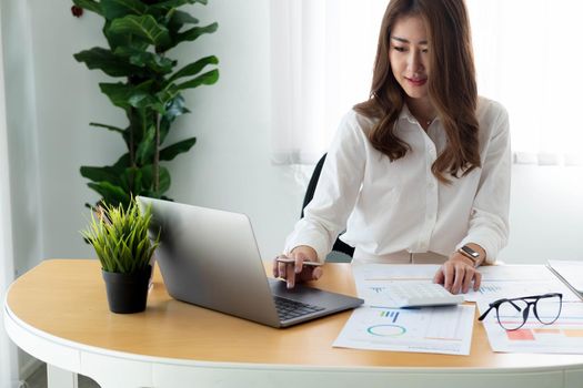 Close up Businesswoman using calculator and laptop for calaulating finance, tax, accounting, statistics and analytic research concept