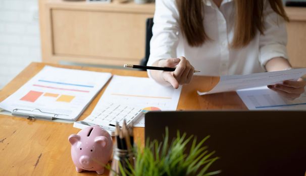 Business woman using calculator for do math finance on wooden desk in office and business working background, tax, accounting, statistics and analytic research concept.