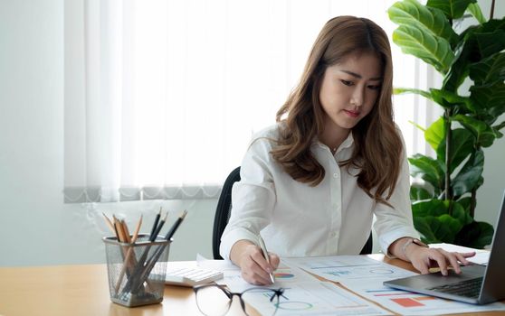 Close up Businesswoman using calculator and laptop for calaulating finance, tax, accounting, statistics and analytic research concept