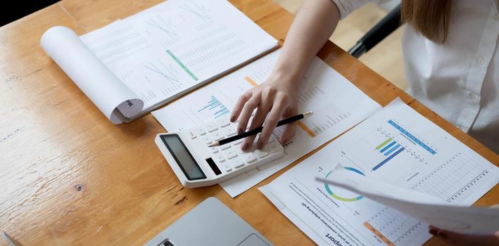 Business woman using calculator for do math finance on wooden desk in office and business working background, tax, accounting, statistics and analytic research concept.