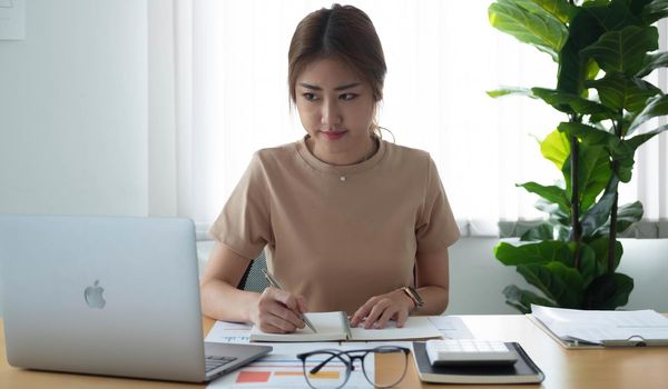 Close up Businesswoman using calculator and laptop for calaulating finance, tax, accounting, statistics and analytic research concept