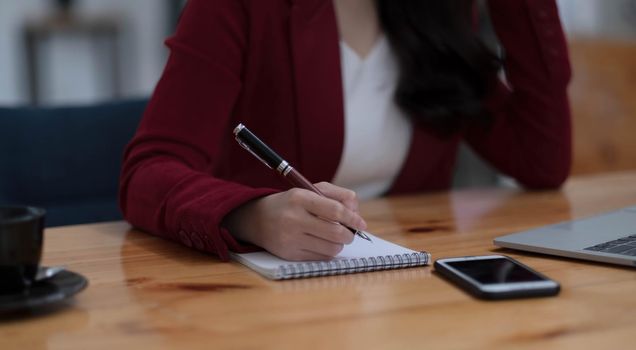 Close up of businesswoman or accountant hand holding pencil working on calculator to calculate financial data report, accountancy document and laptop computer at office, business concept..