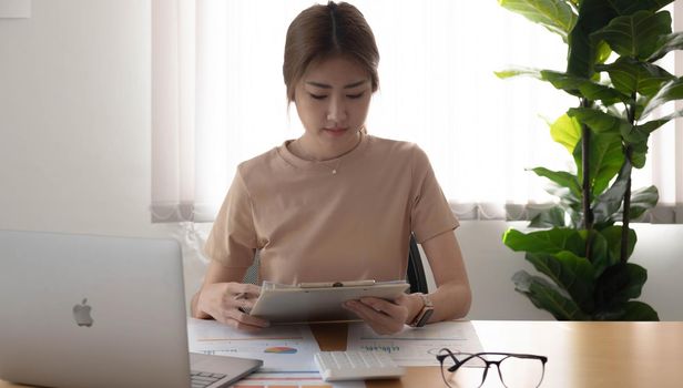 Close up Businesswoman using calculator and laptop for calaulating finance, tax, accounting, statistics and analytic research concept