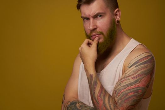 bearded man in white t-shirt with tattoos on his arms posing serious look. High quality photo