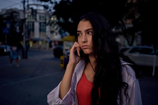 woman talking on the phone outdoors walking in the evening on the street. High quality photo