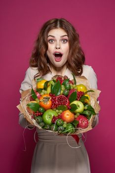 portrait of a woman bright makeup attractive look a bouquet of fruits pink background. High quality photo