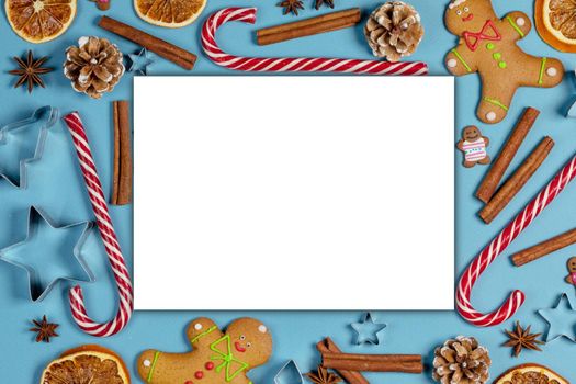 Christmas food background. Gingerbread cookies, candy canes spices and decorations on blue, white greeting card border frame
