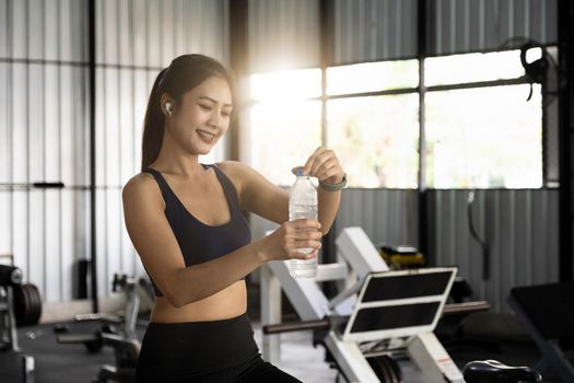 Asian young woman drinking water after workout in gym, healty and sport concept